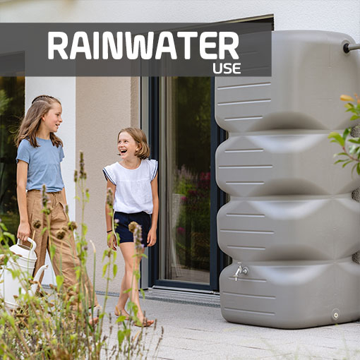 Frau nutzt Regenwasser aus einem Wandtank, um ihre Pflanzen mit einer Gießkanne zu bewässern.