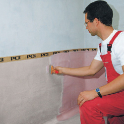 handwerker in roter latzhose gl&auml;ttet mit kelle...