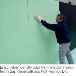 mann schiebt styrodur perimeterdämmplatten grün...